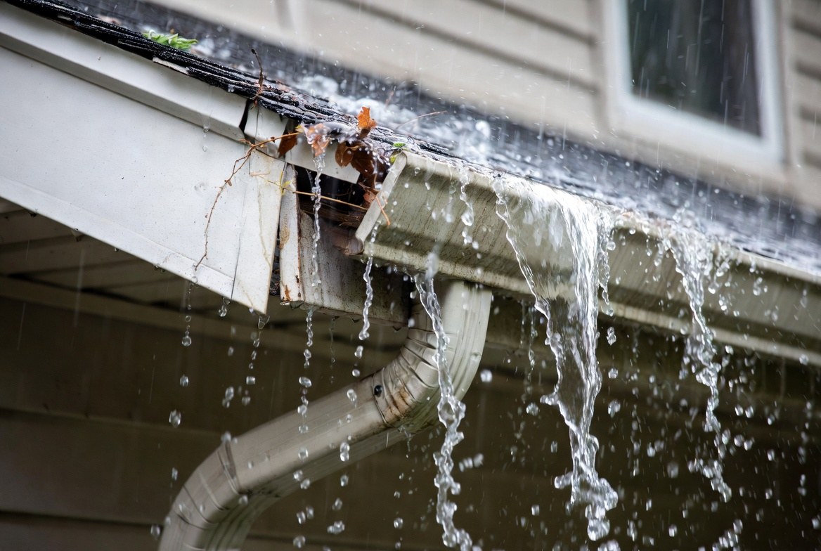 Overflowing damaged gutter during heavy rain